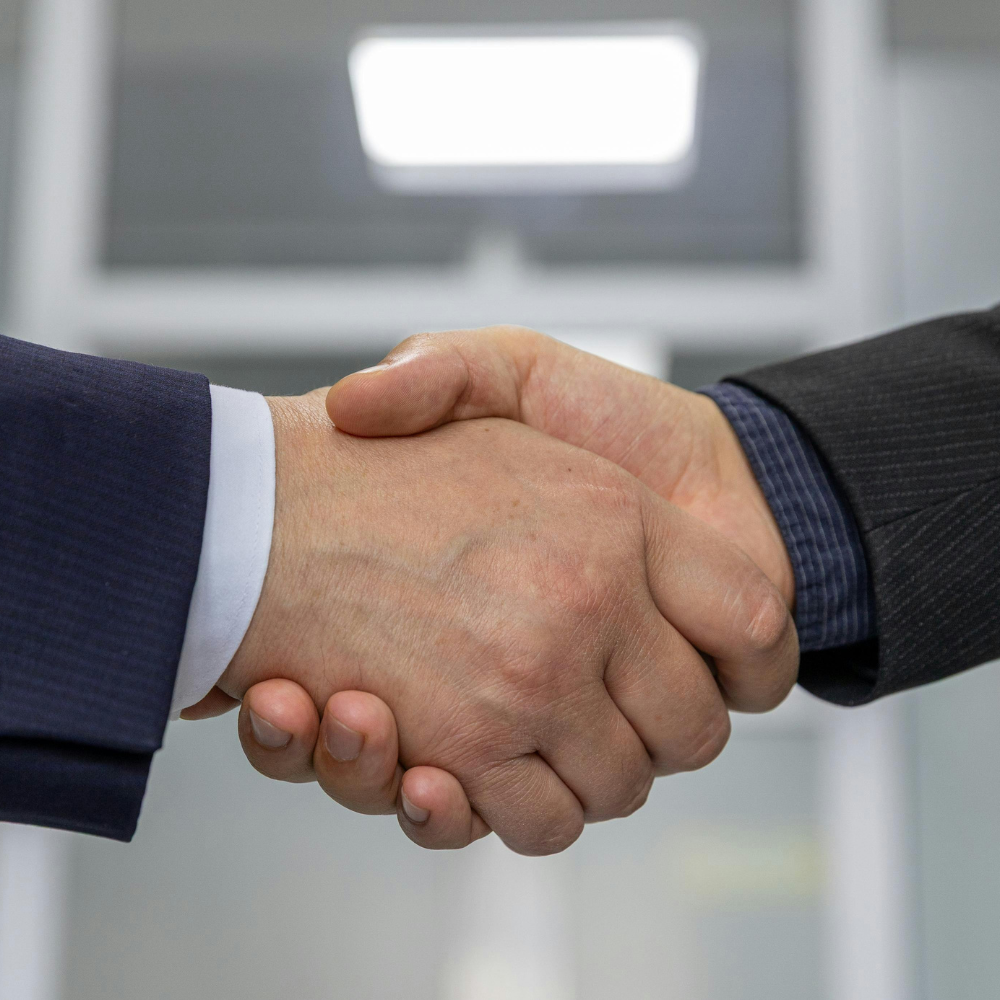Two individuals shaking hands, symbolizing a strategic Business Correspondence partnership enabled by Finpage for financial institutions collaborating on last-mile service delivery